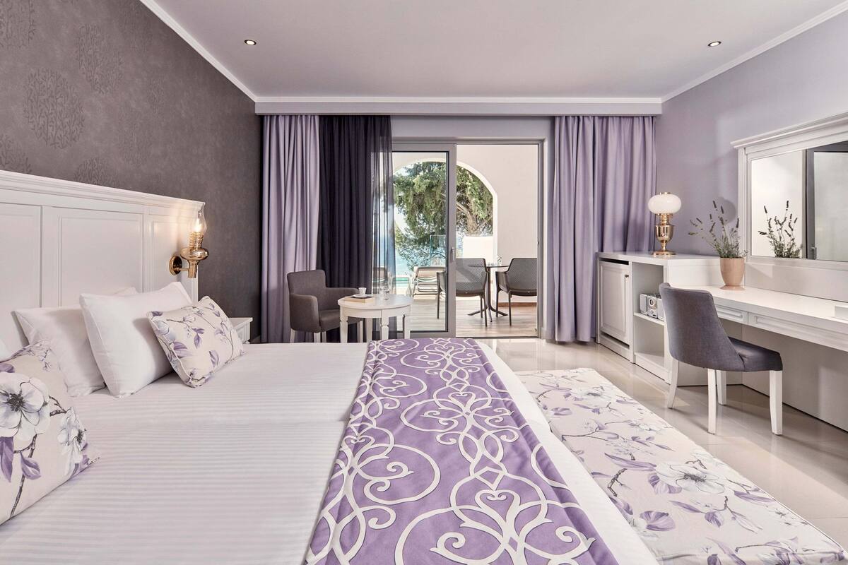Une chambre d’hôtel équipée d’un lit, d’un bureau, d’une chaise et offrant une vue sur l’extérieur.