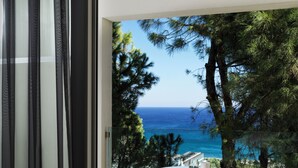 Un balcon avec vue sur la mer, des meubles en osier et une porte vitrée.