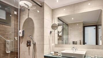 Une salle de bain moderne avec une douche à parois de verre, un grand miroir et un plan de toilette en marbre avec un lavabo.