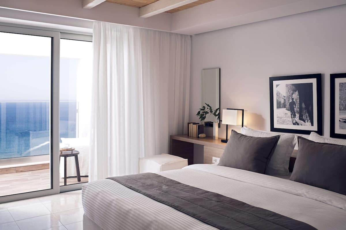 Une chambre à coucher moderne avec un grand lit, une table de chevet avec une lampe, un miroir et des tableaux encadrés accrochés au mur.