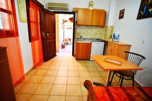 A compact kitchen with wooden cabinets, a small dining table, and a chair.
