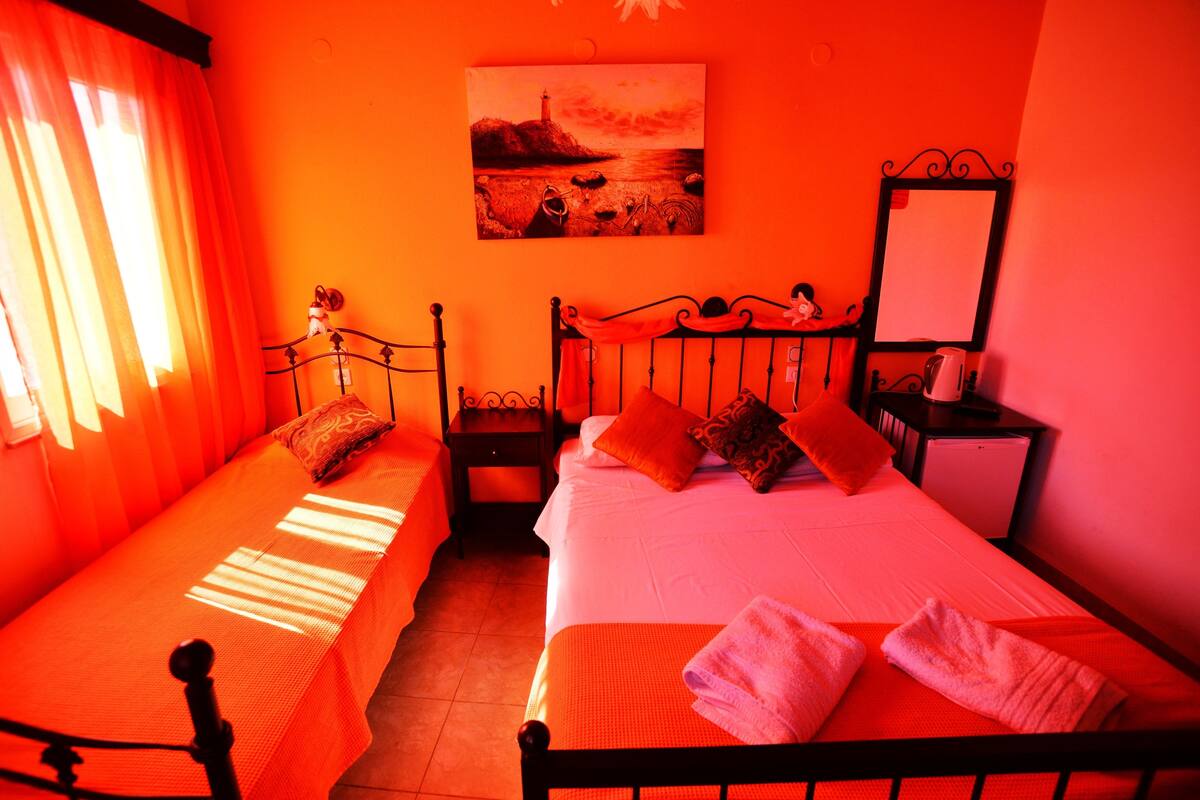 A room with two beds, a painting on the wall, and a nightstand with a lamp.