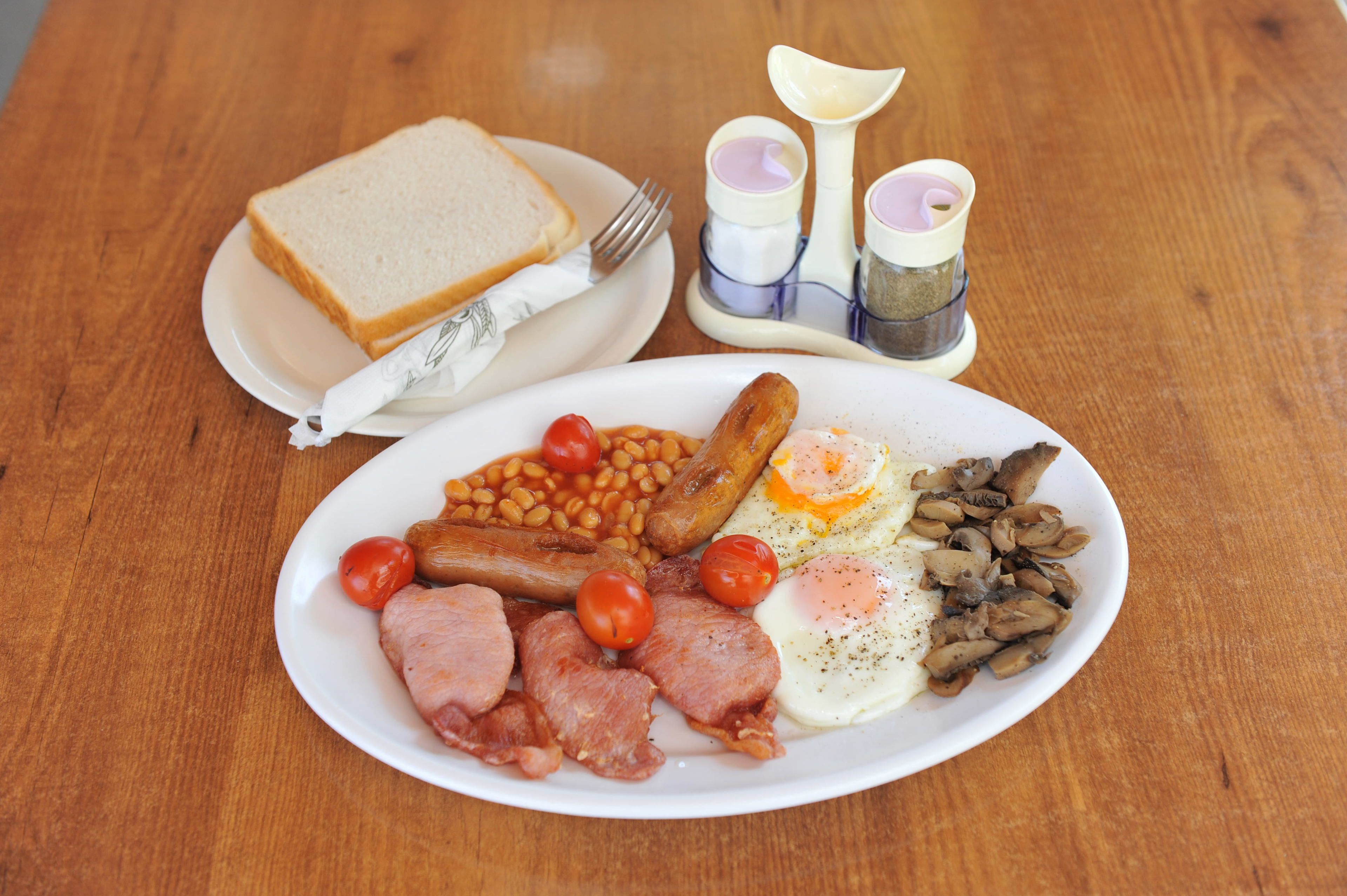 A plate of breakfast food including eggs, sausages, tomatoes, and beans.