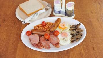 A plate of breakfast food including eggs, sausages, tomatoes, and beans.