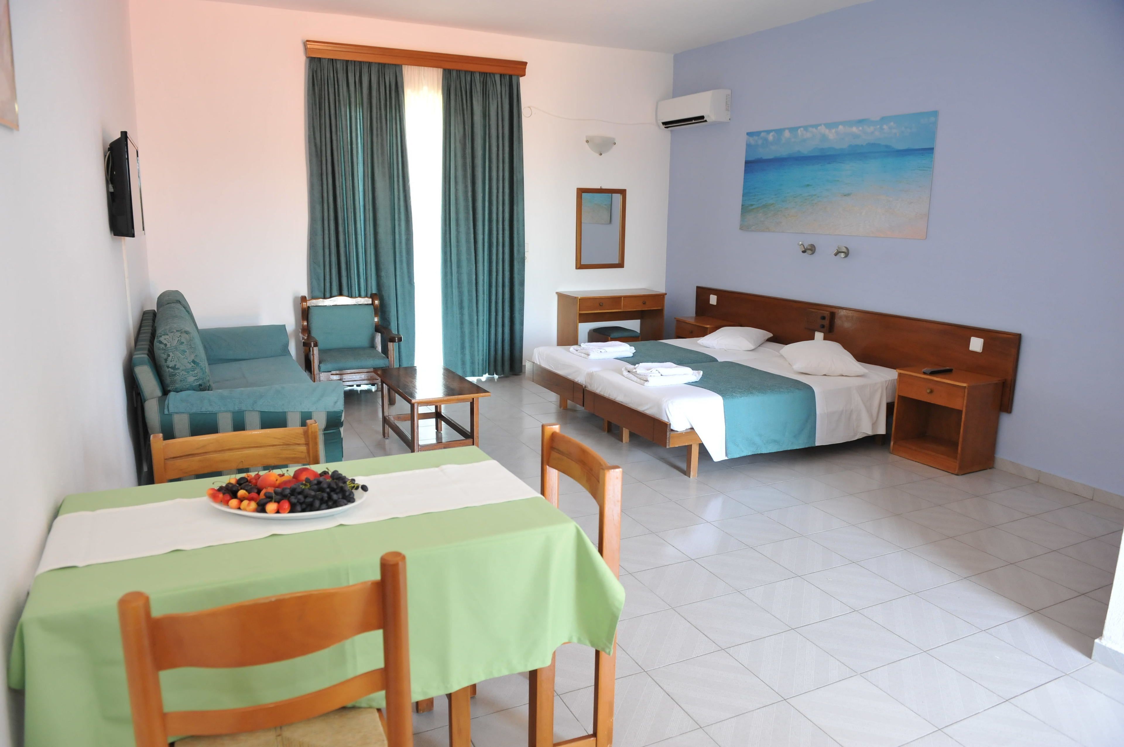 A hotel room with a bed, a sofa, a desk, and a dining area with a table and chairs.