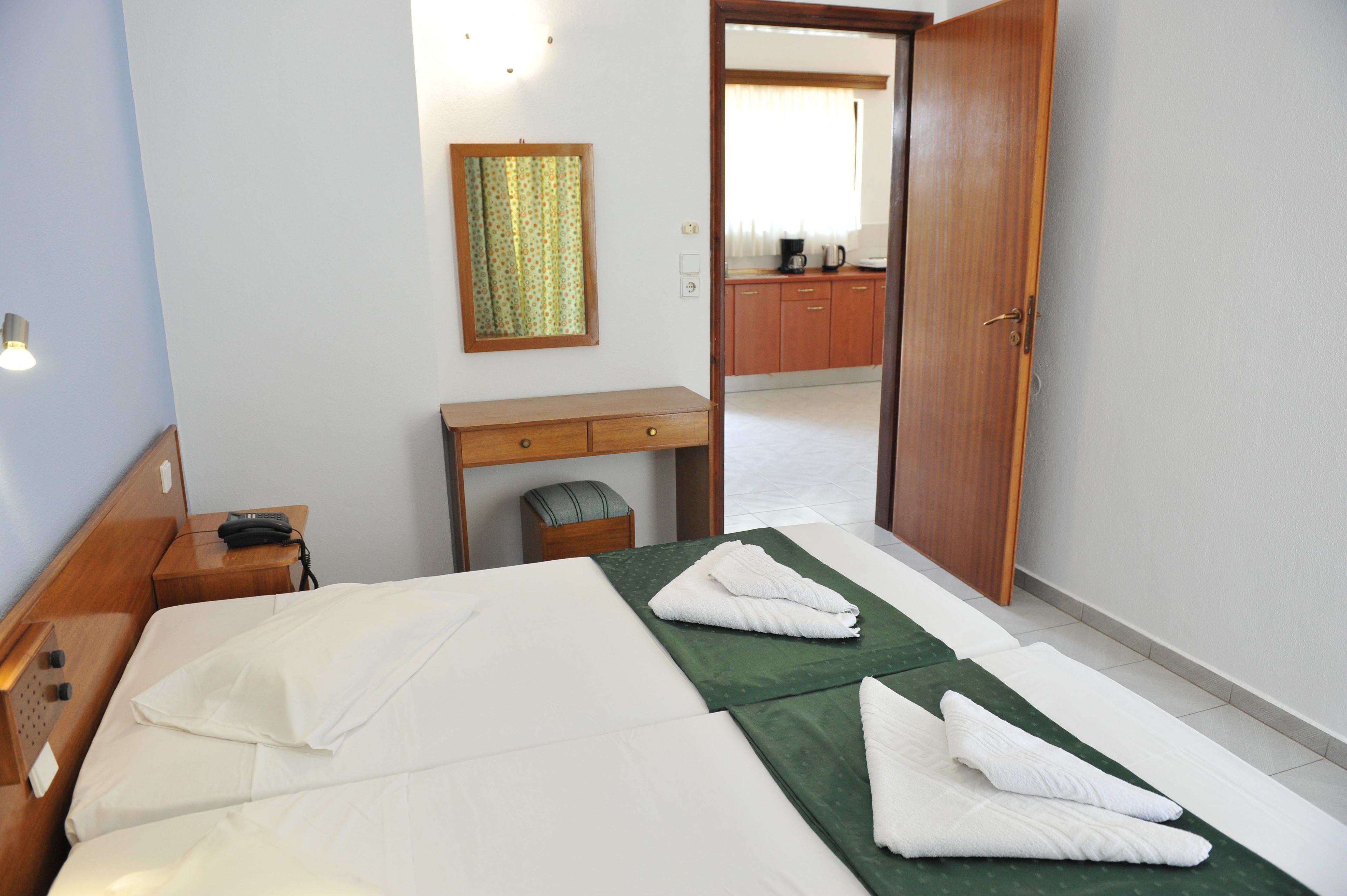 A hotel room with a bed, a desk, a chair, a telephone, and a mirror.