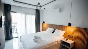 Une chambre d’hôtel moderne avec un grand lit, une table de chevet, une commode et une vue sur l’extérieur.