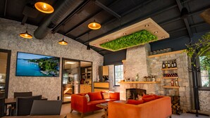 Un intérieur moderne avec une cheminée, des canapés orange et un téléviseur diffusant un paysage pittoresque.