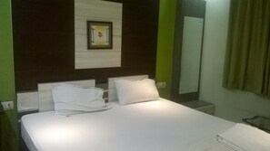 Une chambre d’hôtel avec un lit, deux oreillers, une table de chevet, un miroir et un tableau encadré au mur.