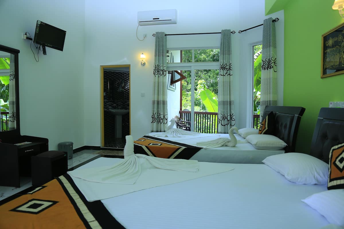 A hotel room with two beds, a TV mounted on the wall, and a window with curtains.