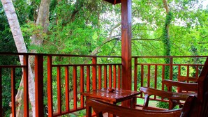 A wooden deck with a table and chairs, surrounded by trees. - Hotel River Front (Thissamaharama)