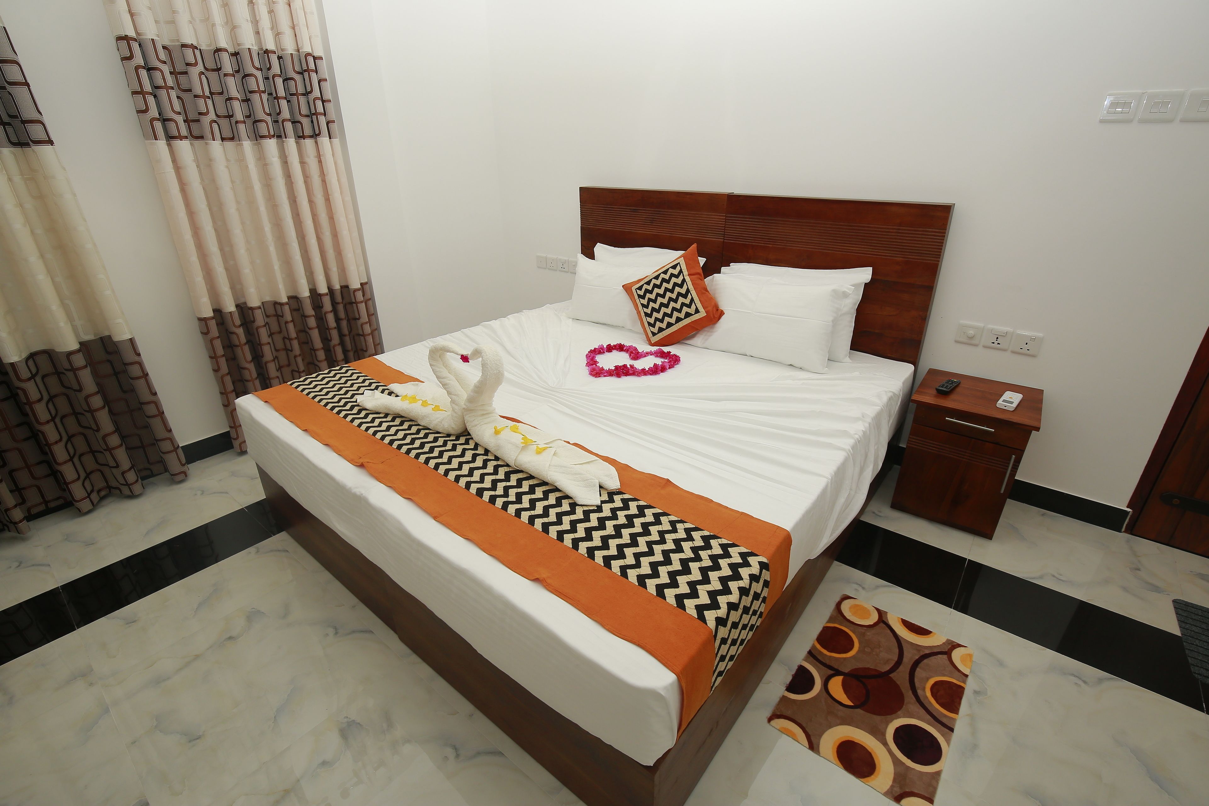 A neatly made bed with a patterned bedspread, a pillow with a zigzag design, and a heart-shaped decoration on the bed.