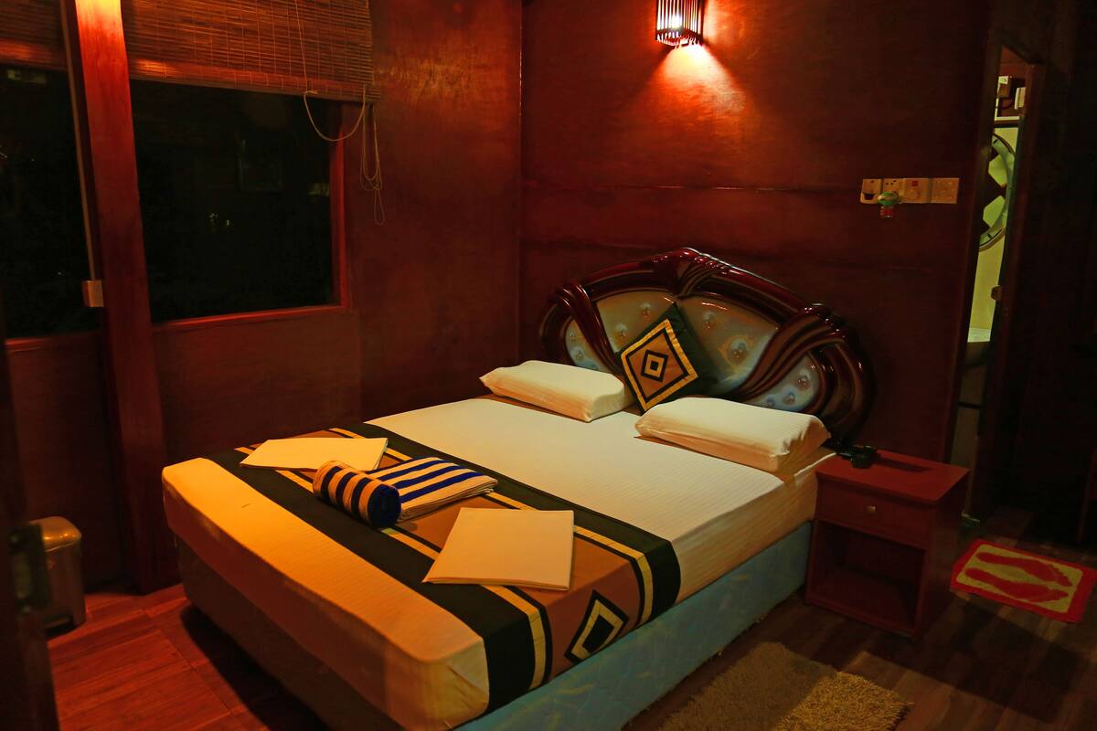 A neatly made bed with a patterned bedspread, a bedside table, and a wall-mounted light fixture.