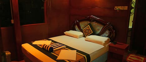 A neatly made bed with a patterned bedspread, a bedside table, and a wall-mounted light fixture.