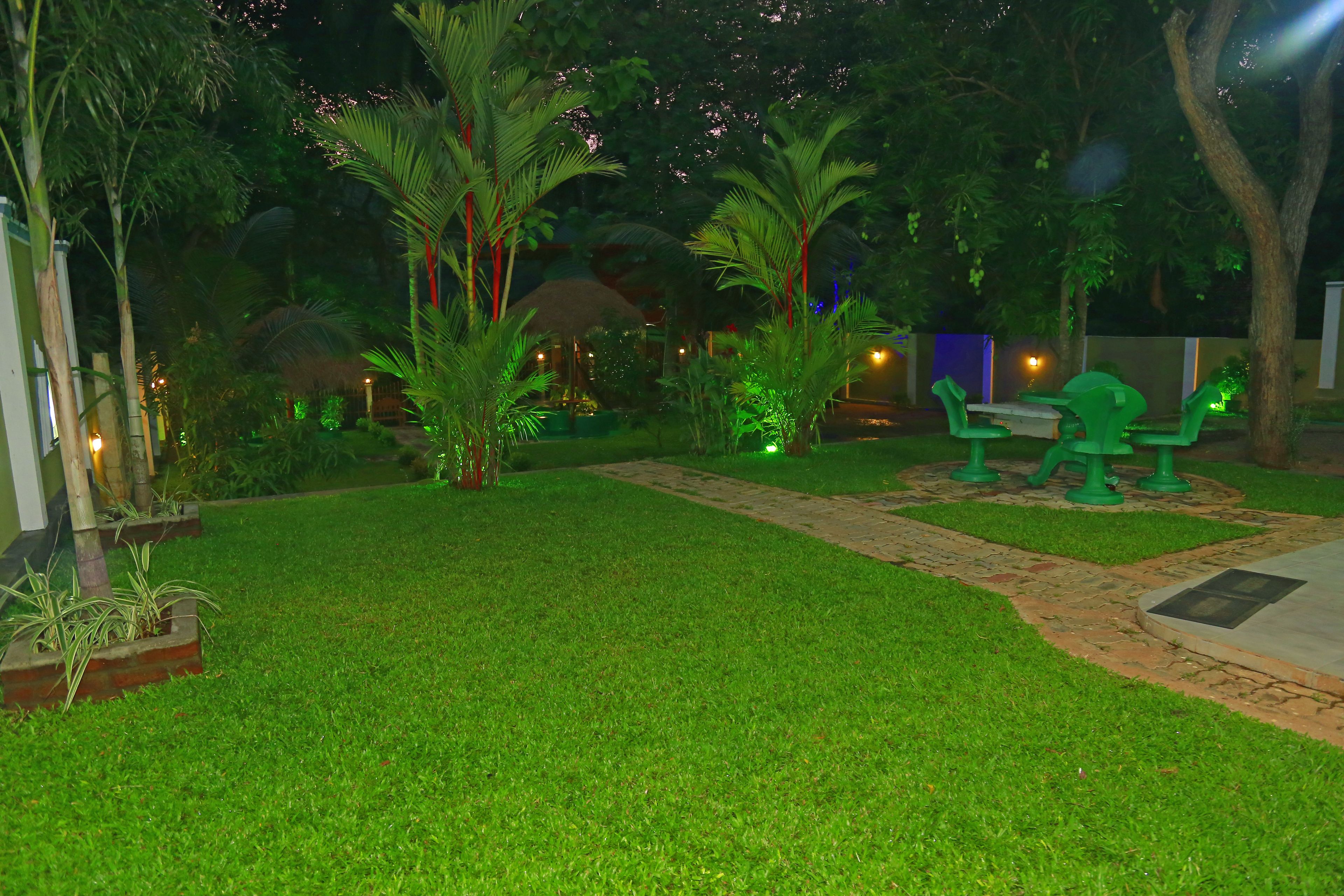 A well-maintained garden with a pathway, green seating area, and palm trees.