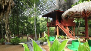 A wooden structure with a thatched roof, surrounded by lush greenery and a small pool area. - Hotel River Front (Thissamaharama)