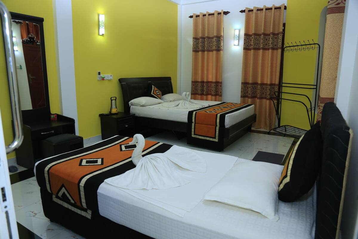 A hotel room with two beds, a mirror, a nightstand, a lamp, and a shower area.