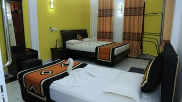 A hotel room with two beds, a mirror, a bedside table, a lamp, and a window with curtains.