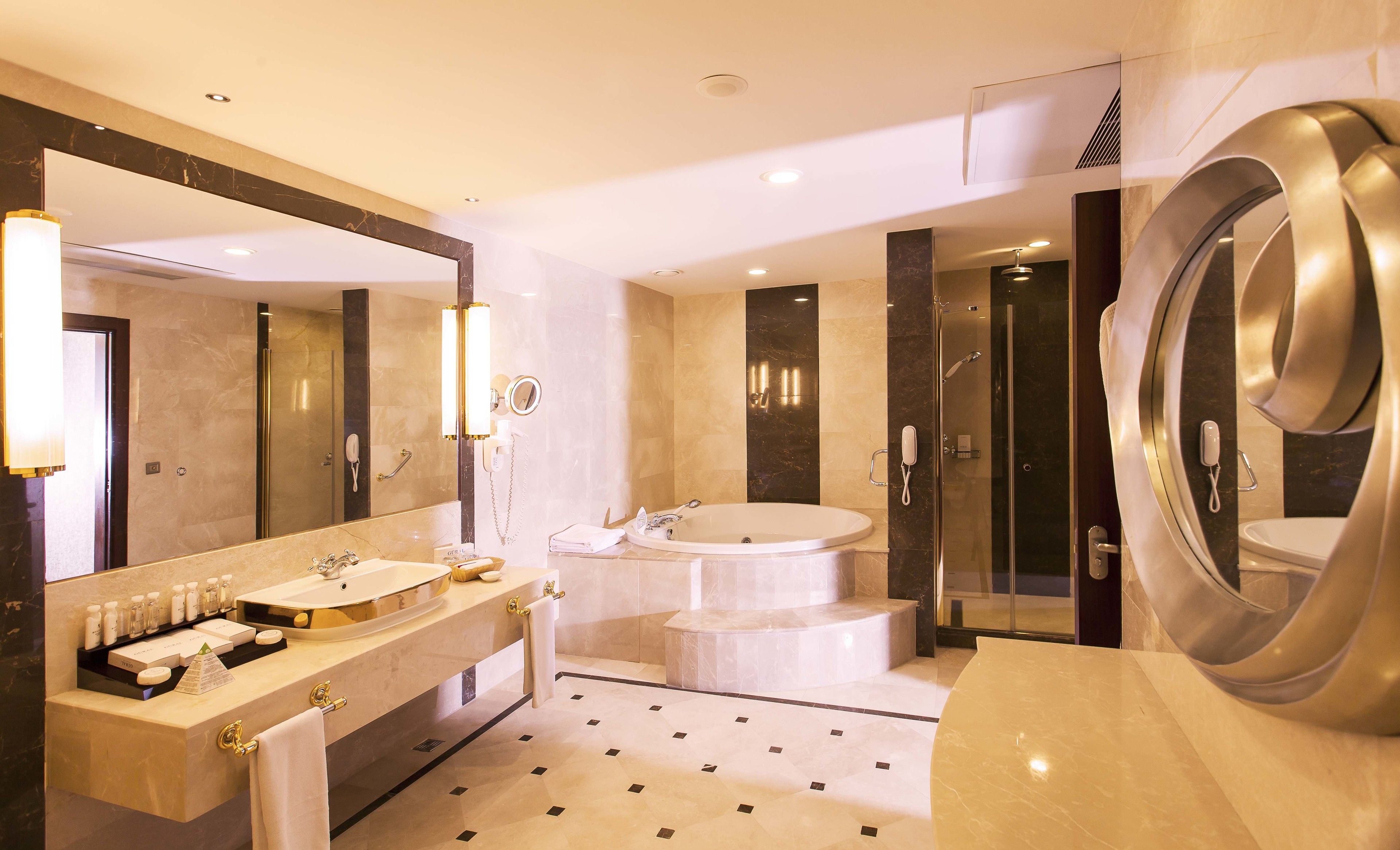 A modern bathroom with a large mirror, dual sinks, a bathtub, and a walk-in shower.