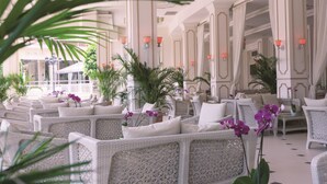 A spacious indoor seating area with wicker furniture and potted plants. - Güral Premier Tekirova - All Inclusive (Kemer)