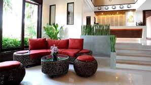 Un moderno hall de entrada con un sofá rojo, una mesa de centro de vidrio y un mostrador de recepción.