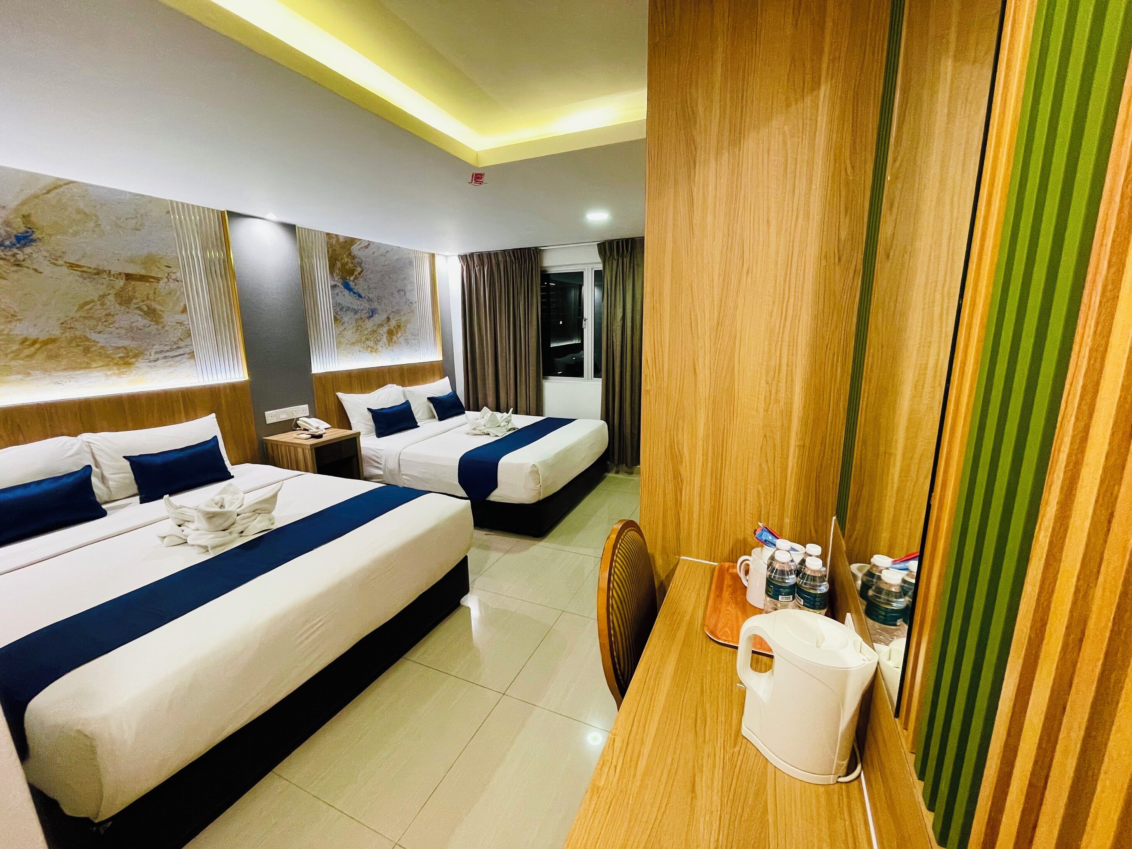 A hotel room with two beds, a wooden desk, a kettle, and a map on the wall.