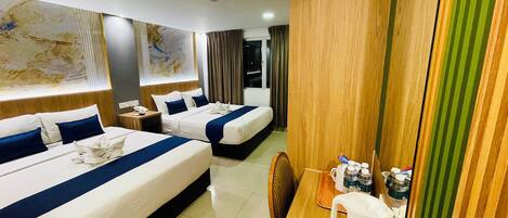 Habitación de hotel con dos camas, un escritorio de madera, una tetera y un mapa en la pared.
