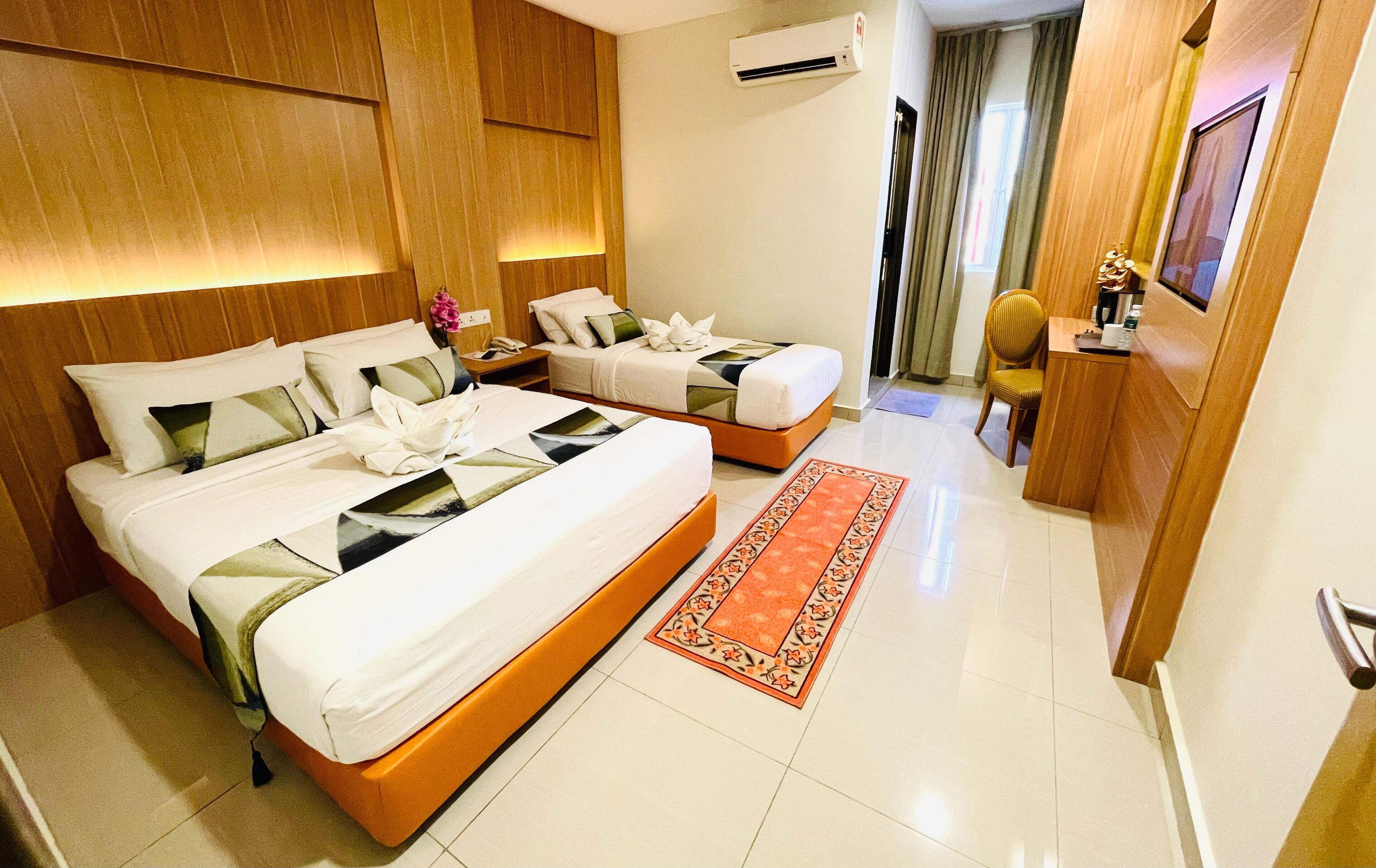 A hotel room with two beds, a wooden headboard, a small desk, a chair, and a red rug.