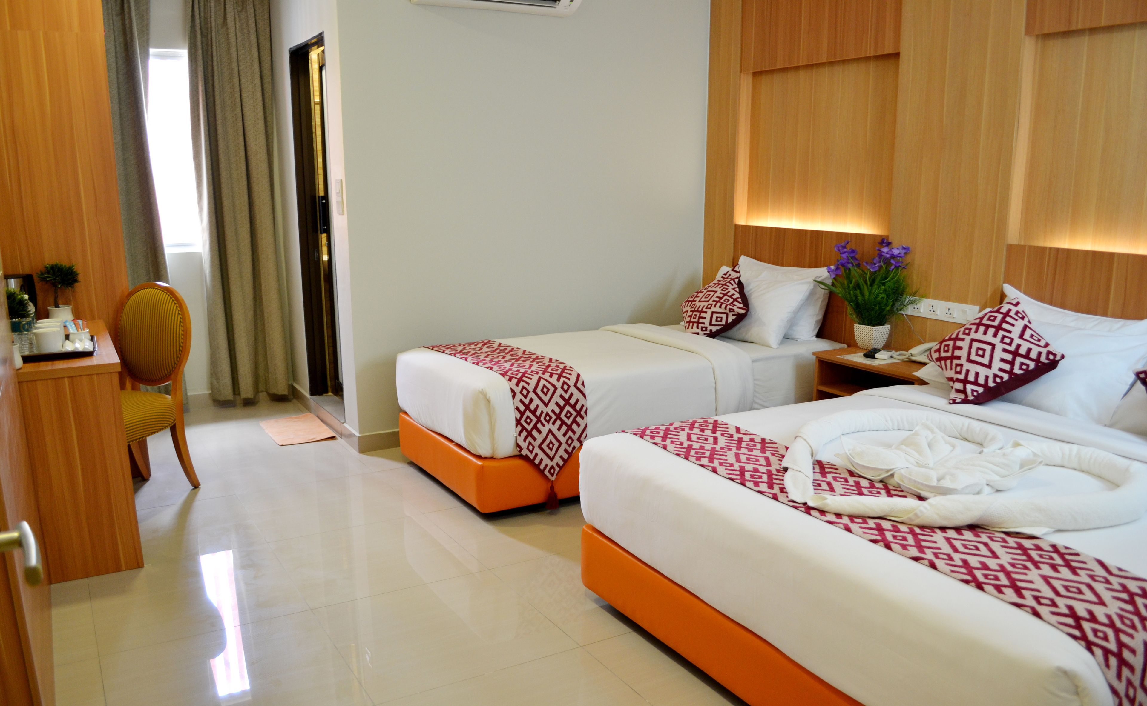 A hotel room with two beds, a desk, and a chair.