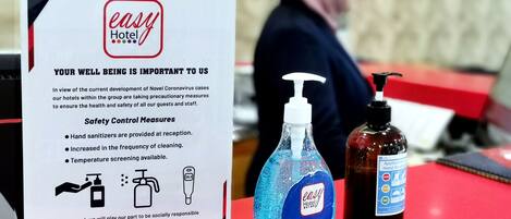 A hotel sign detailing safety measures, including hand sanitizer and temperature screening.