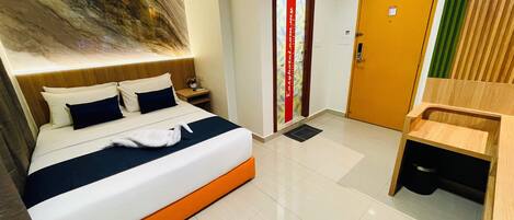 A hotel room with a bed, a nightstand, a wooden bench, a door with a red stripe, and a wall with a marble-like design.