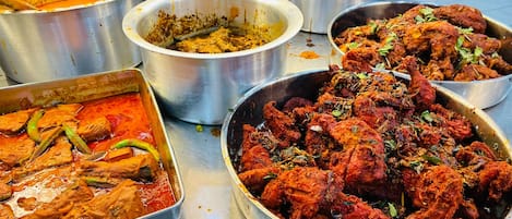A variety of food dishes in metal containers, including what appears to be chicken and curry.