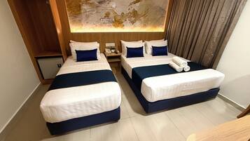 A hotel room with two beds, a small desk, a nightstand, and a large abstract wall art piece.