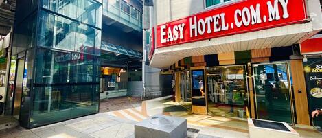 Exterior del Easy Hotel, con fachada de vidrio y un llamativo letrero rojo.