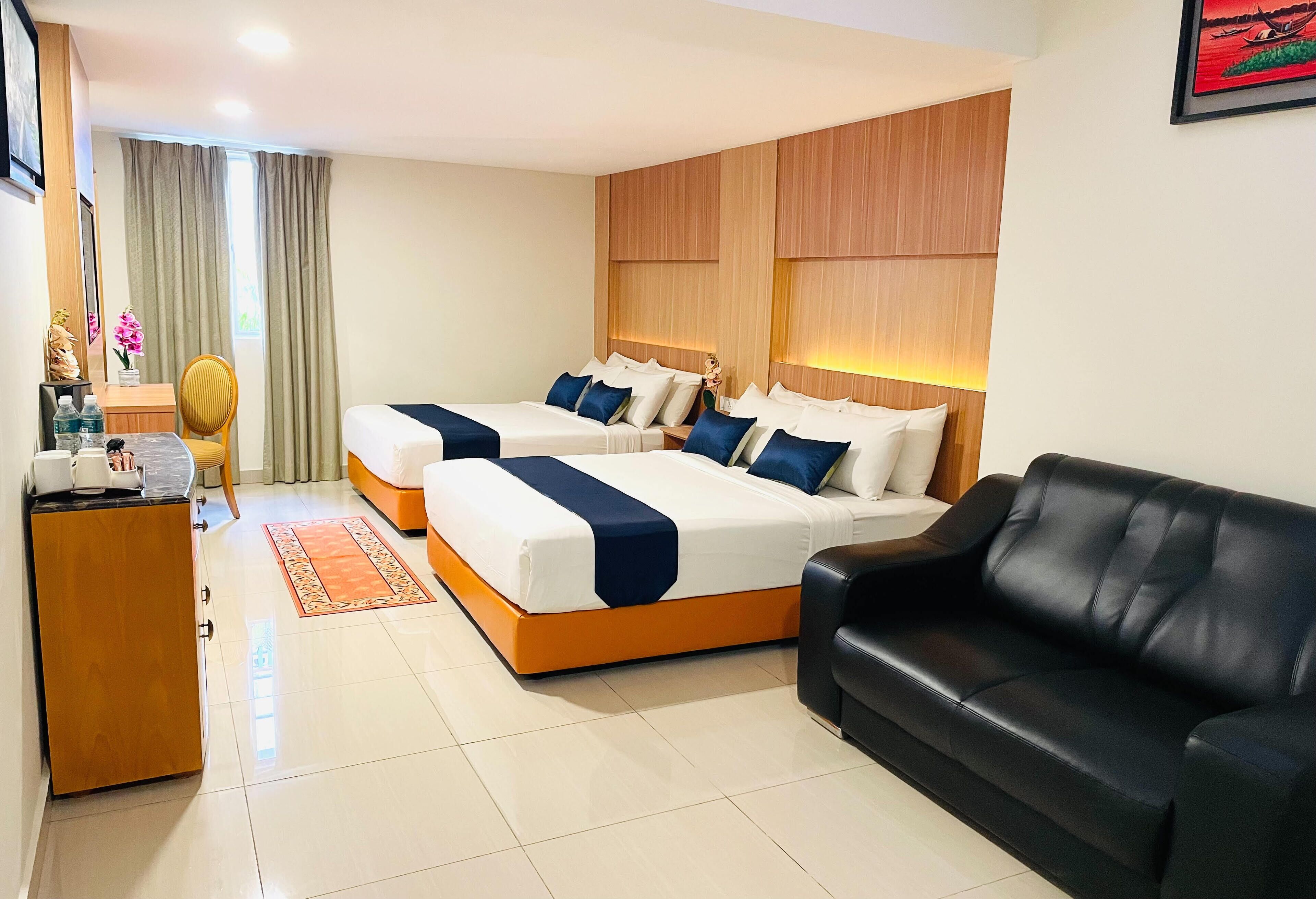 A hotel room with two beds, a sofa, a desk with a chair, and a window with curtains.