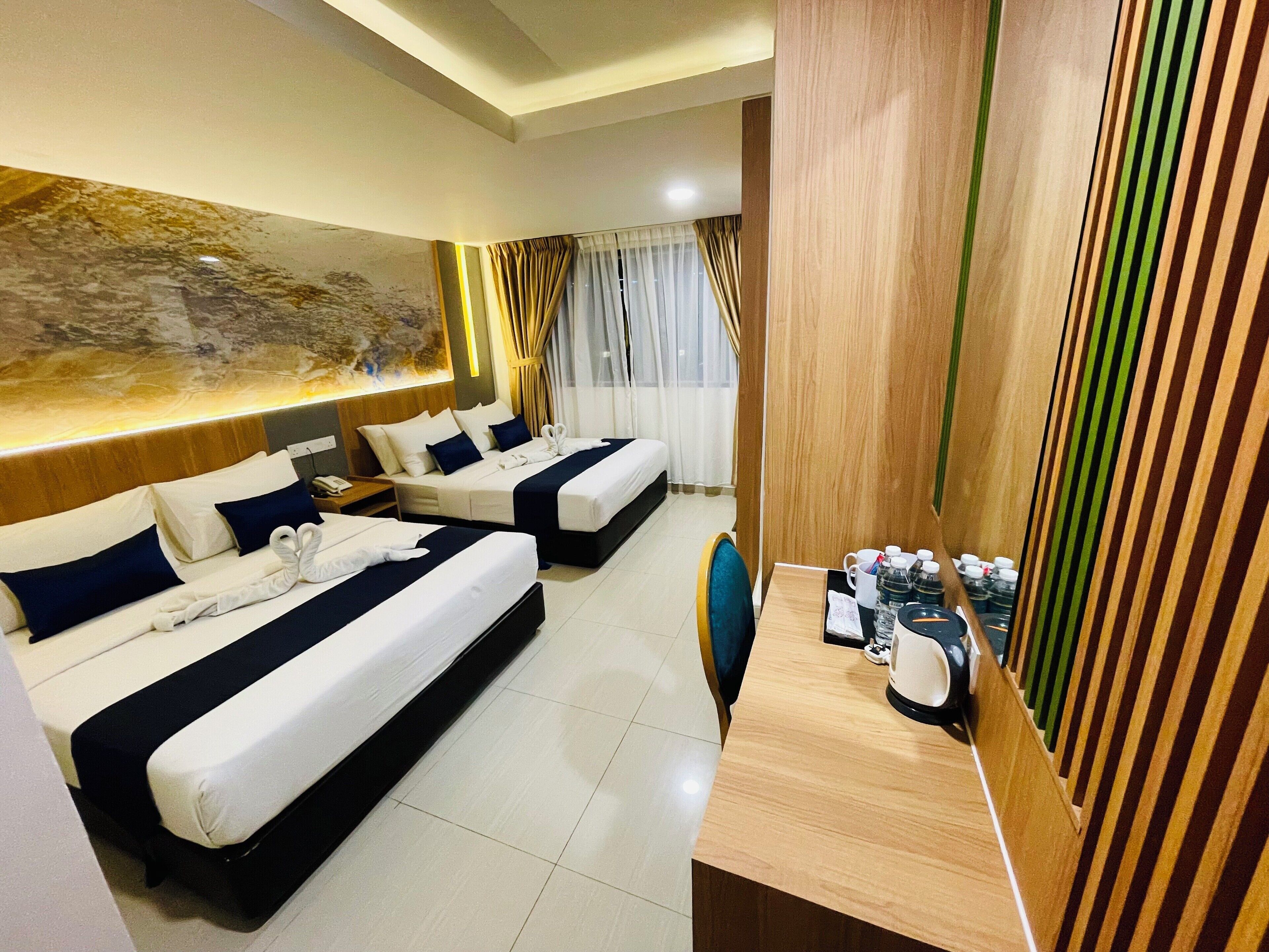 Une chambre d’hôtel avec deux lits, un bureau en bois et un grand tableau abstrait accroché au mur.