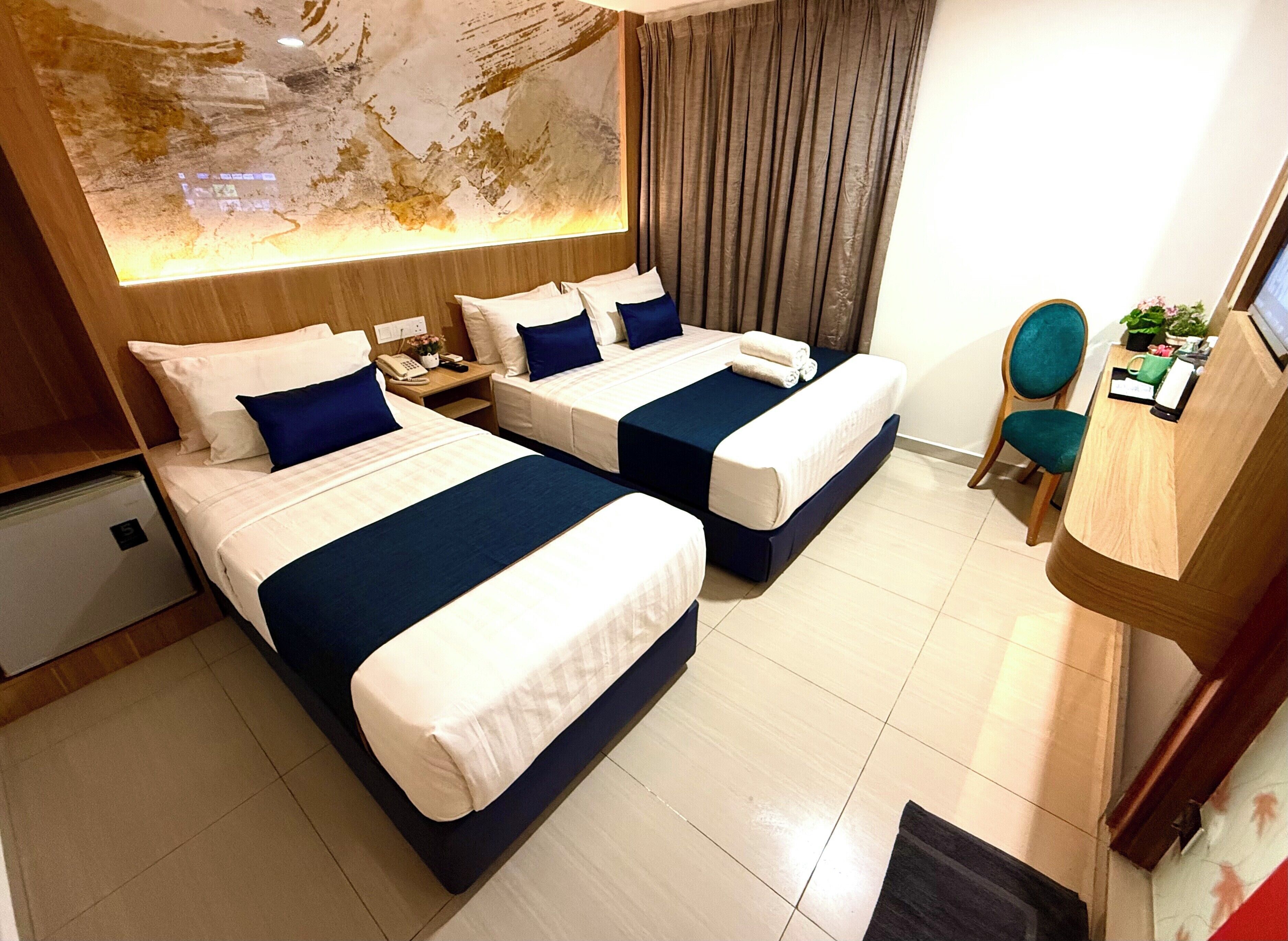 A hotel room with two beds, a desk, a chair, and a large abstract wall art.