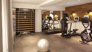 Un gimnasio moderno con cintas de correr, elípticas y una máquina de remo.