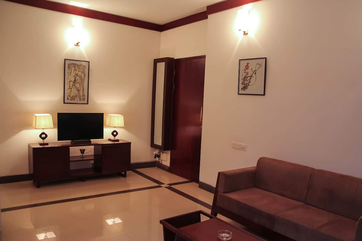 A living room with a sofa, a TV, two lamps, a mirror, and artwork on the walls.