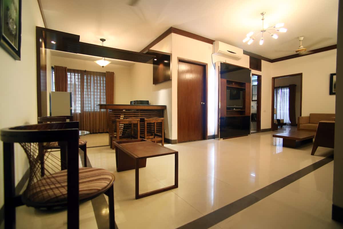 A spacious living room with a wooden coffee table, a sofa, and a dining area with chairs.