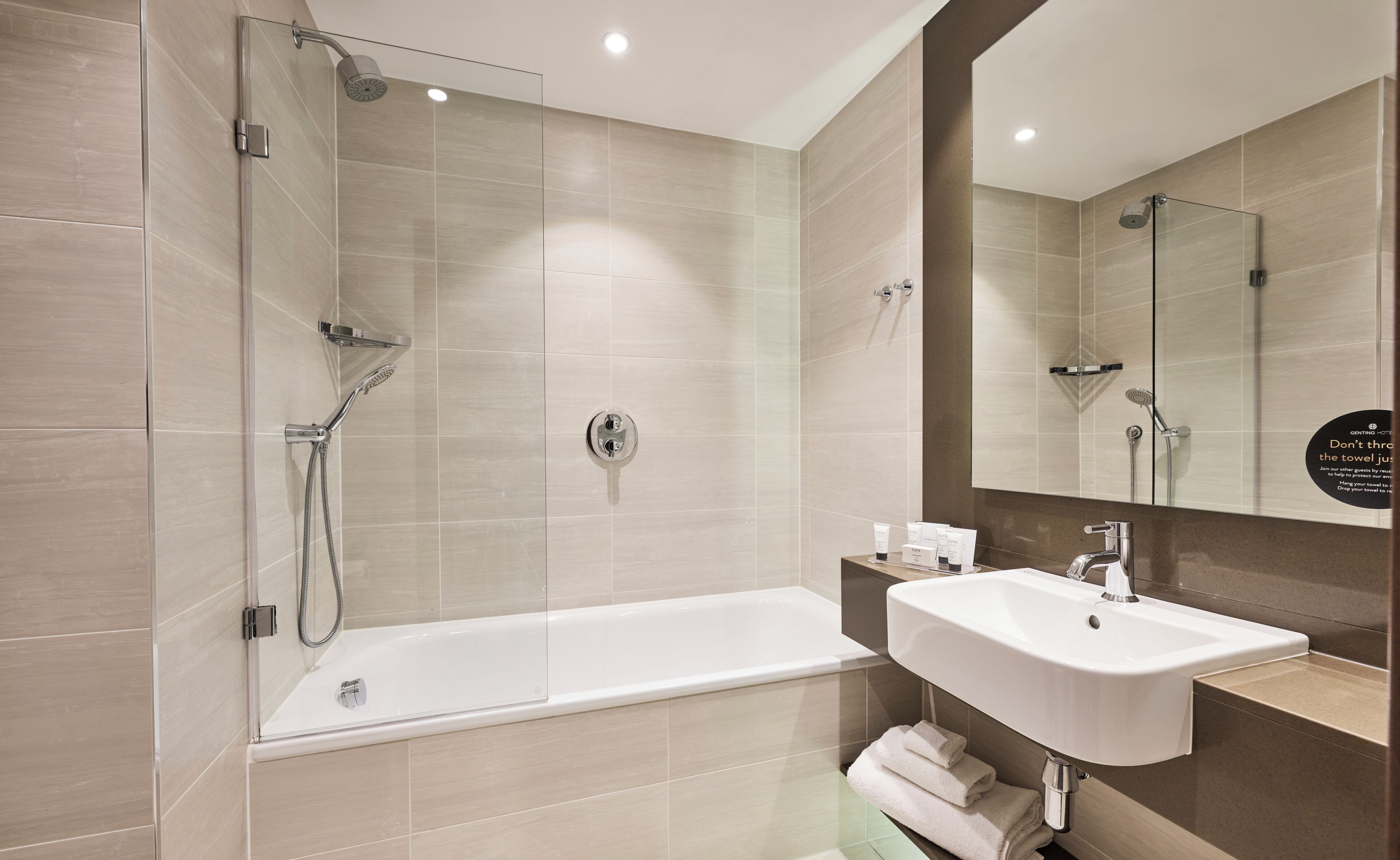 Un baño moderno con ducha envuelta en vidrio, una bañera independiente y un lavamanos con espejo.