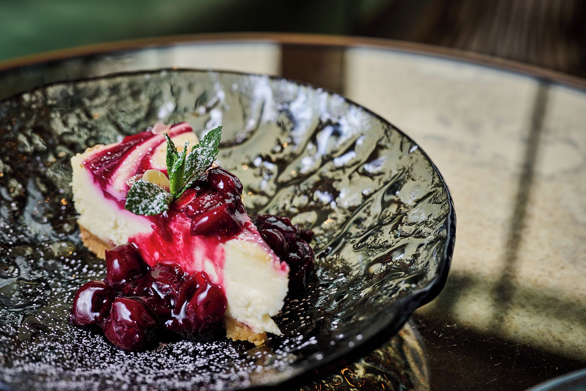 A dessert on a textured plate with berries and mint garnish.