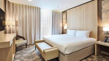 Hotelkamer met een groot bed, een bureau, een stoel, een bankje en een telefoon aan de muur.