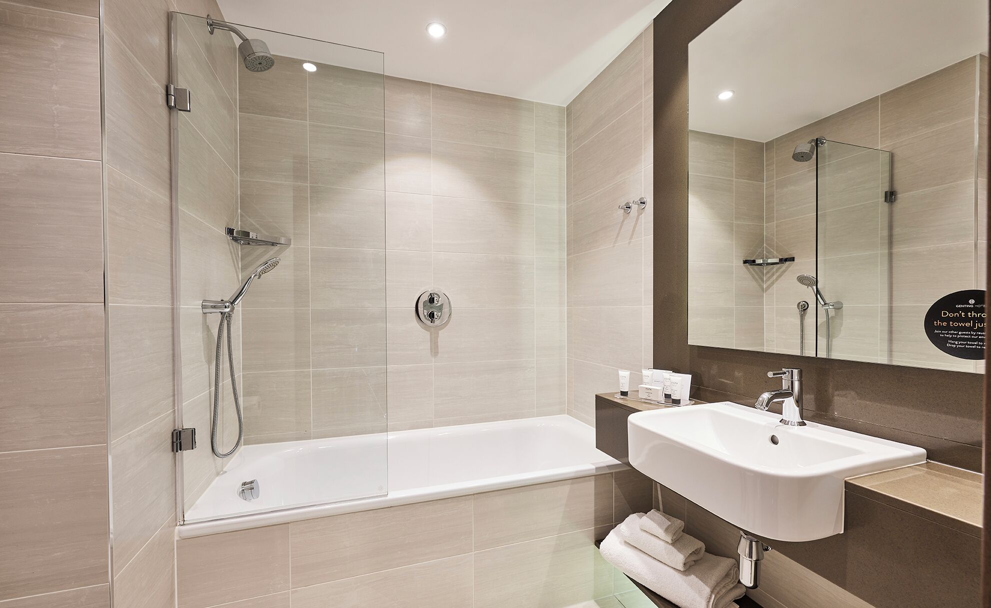 A modern bathroom with a glass-enclosed shower, a standalone bathtub, and a sink with a mirror above it.