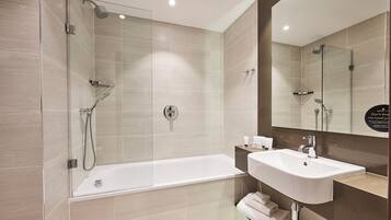 A modern bathroom with a glass-enclosed shower, a standalone bathtub, and a sink with a mirror above it.