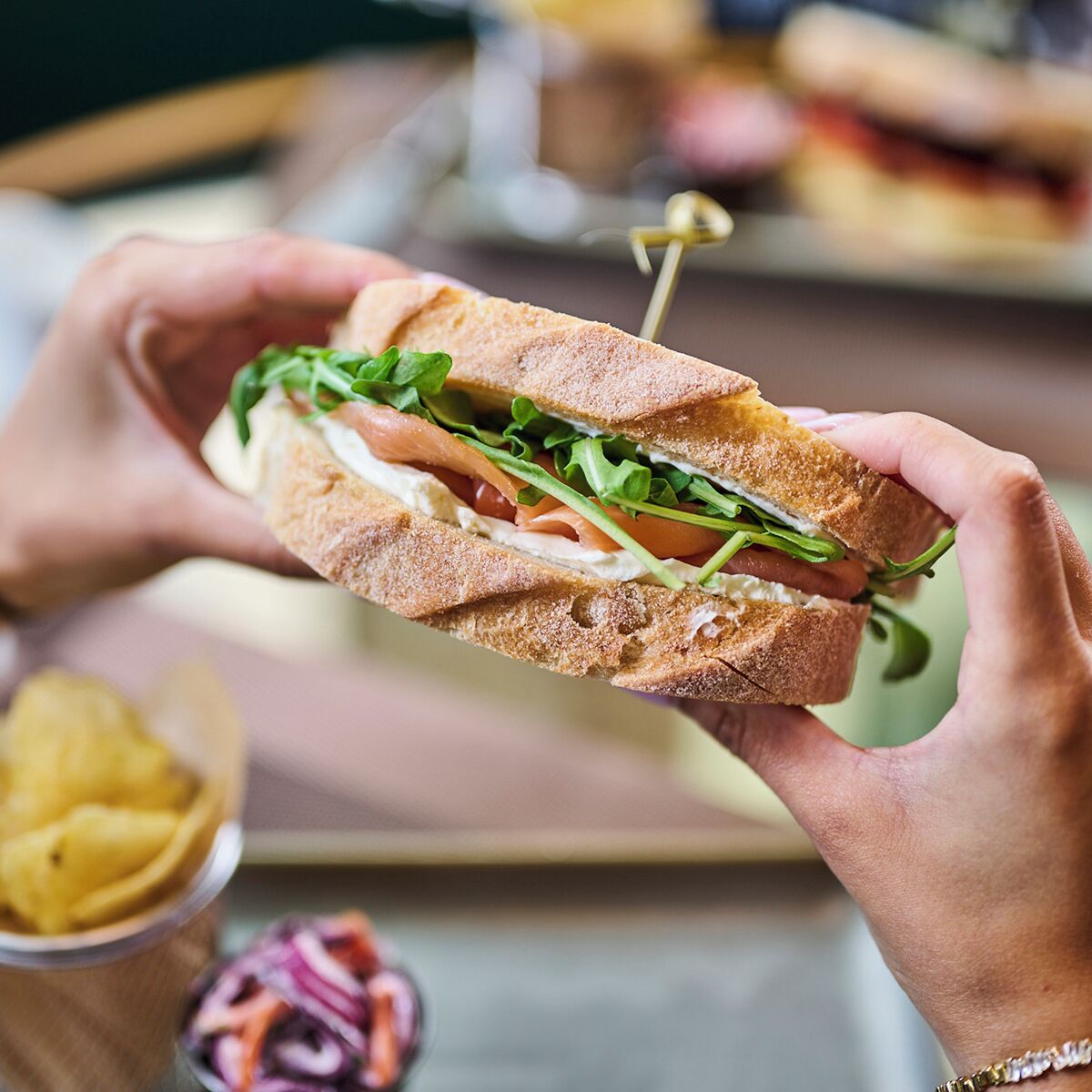 Un sandwich dans lequel on peut voir clairement les ingrédients, comme la laitue et la tomate, et qui est tenu à la main.