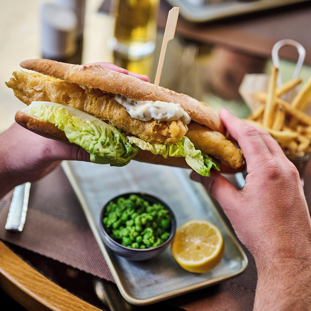 Un sándwich con un palillo, acompañado de papas fritas y un cuenco pequeño de guisantes.