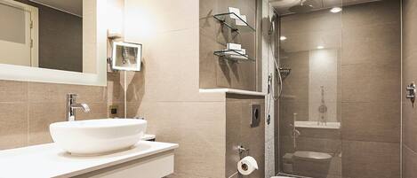 A modern bathroom with a large mirror, a sink, a toilet, and a shower area.
