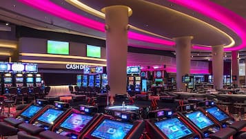 Experience the excitement of gaming at this casino, where multiple tables and slot machines await, surrounded by seating areas and a cash desk.