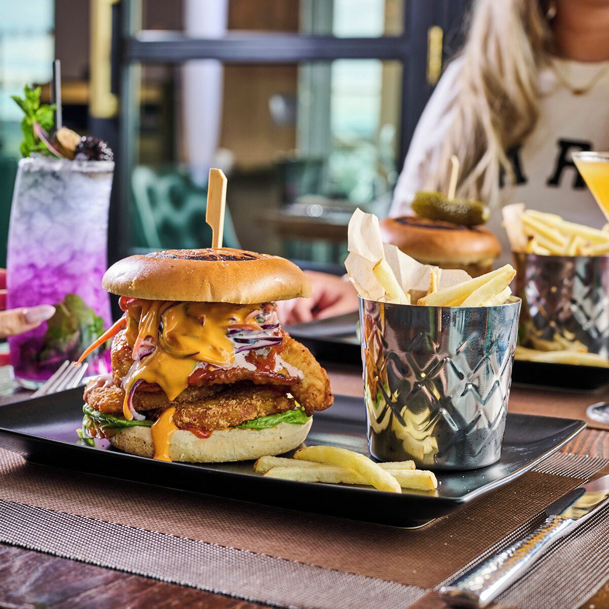 A burger with fries and a drink on a tray.